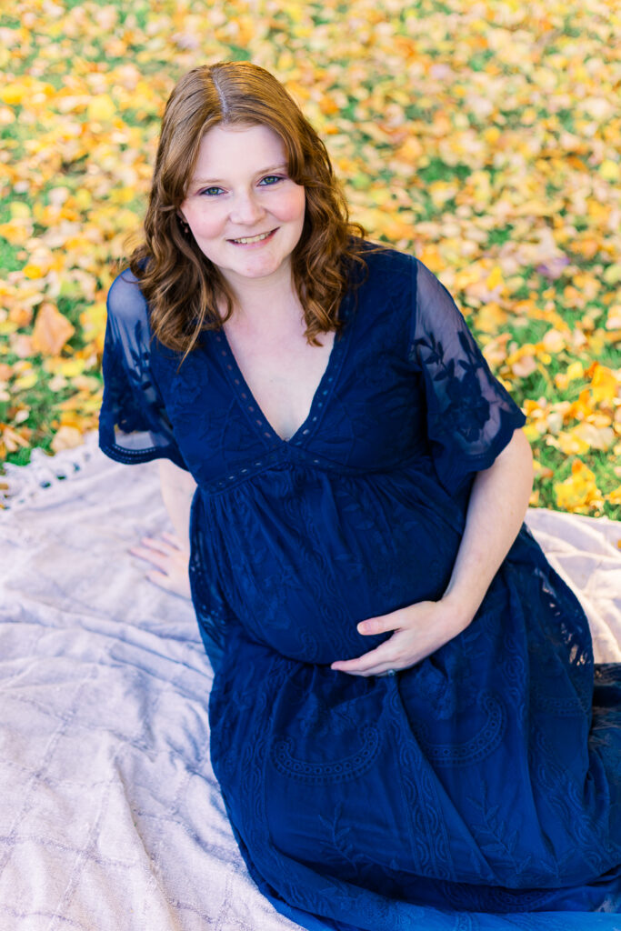 A pregnant mom to be is sitting on a blanket in an outdoor maternity session in Pittsburgh, PA