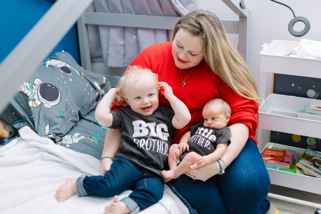 Mom with proud big brother and little brother just hanging out in big brothers room during a lifestyle newborn session in Pittsburgh, PA.