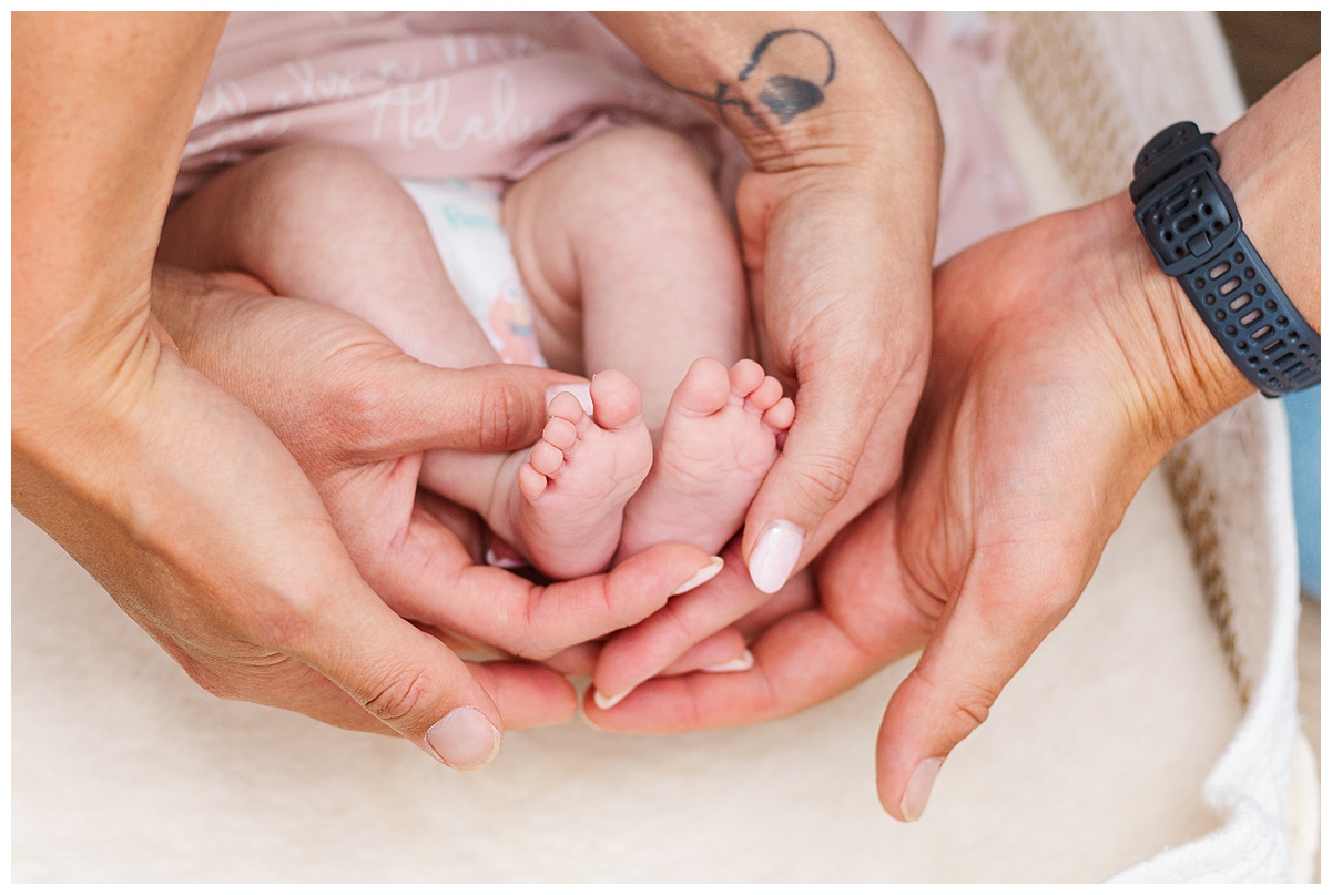 Mom and Dad are holding newborn daughters baby feet during an in home lifestyle newborn session in Pittsburgh, PA