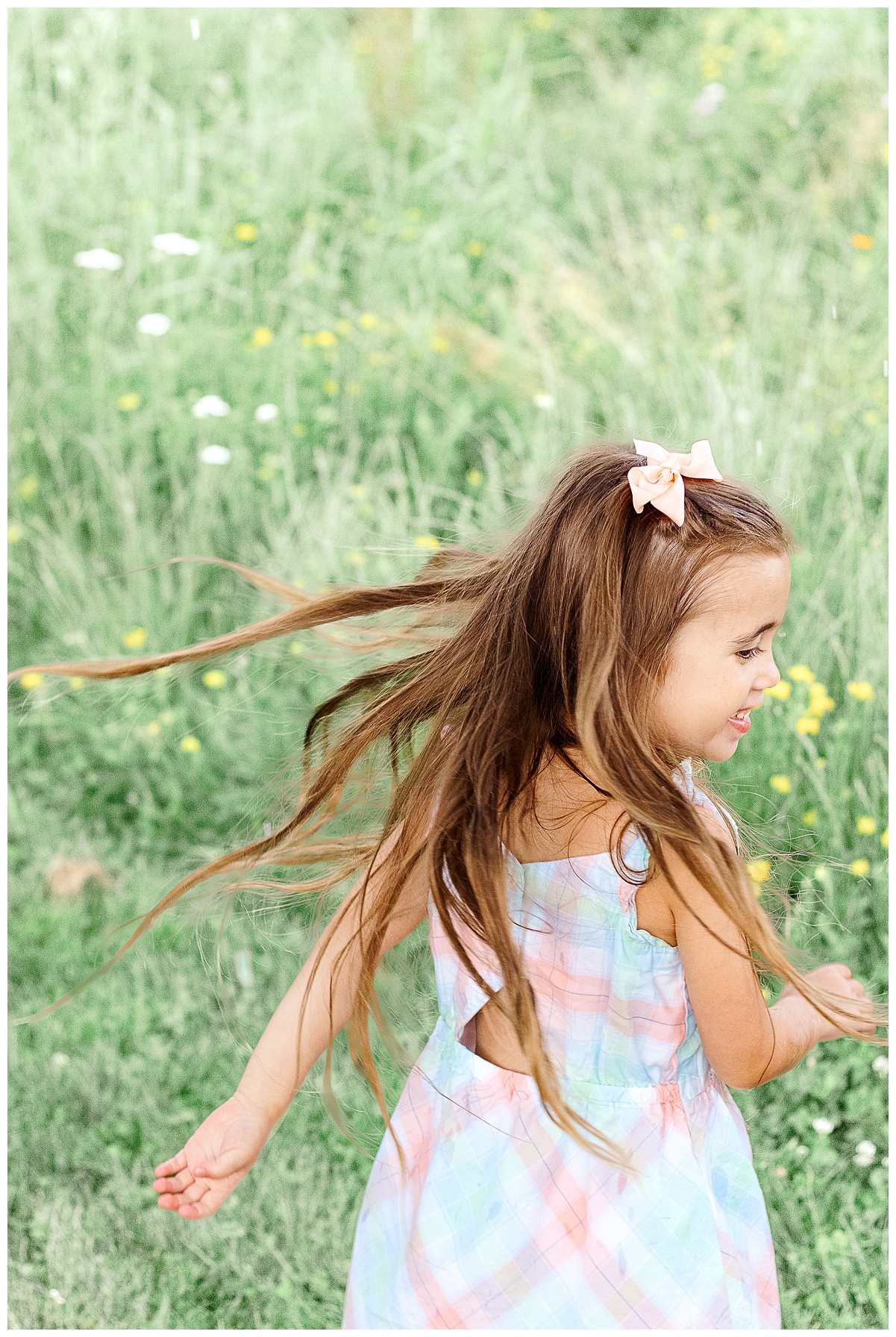 A young girl is twirling around as I capture her beautiful smile and laughs during an outdoor family photo session in Pittsburgh, PA