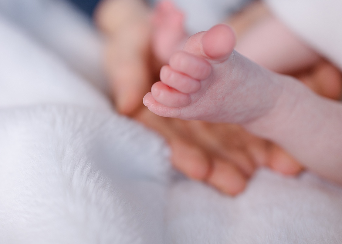 Close-up of tiny baby feet wrapped in a light blanket, photographed by Pittsburgh lifestyle newborn photographer, Shayna VanDamia.