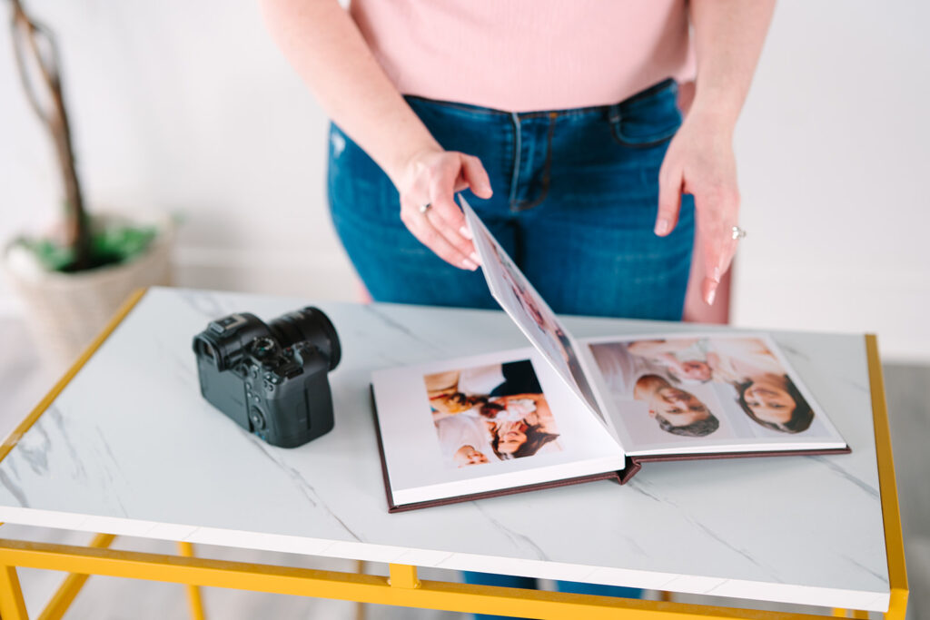photographer looking at an album before giving it to her clients. pictures taken by a Hampton Newborn Photographer