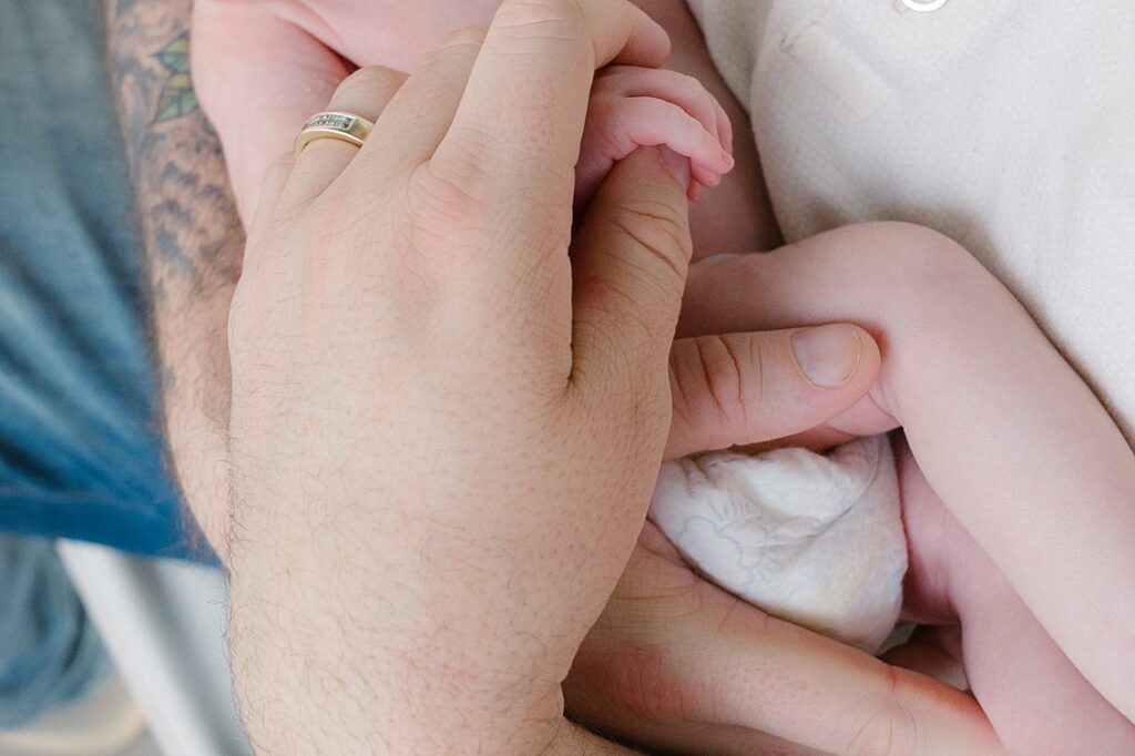 tiny baby boy fingers being held by his dad during his newborn session in Pittsburgh.