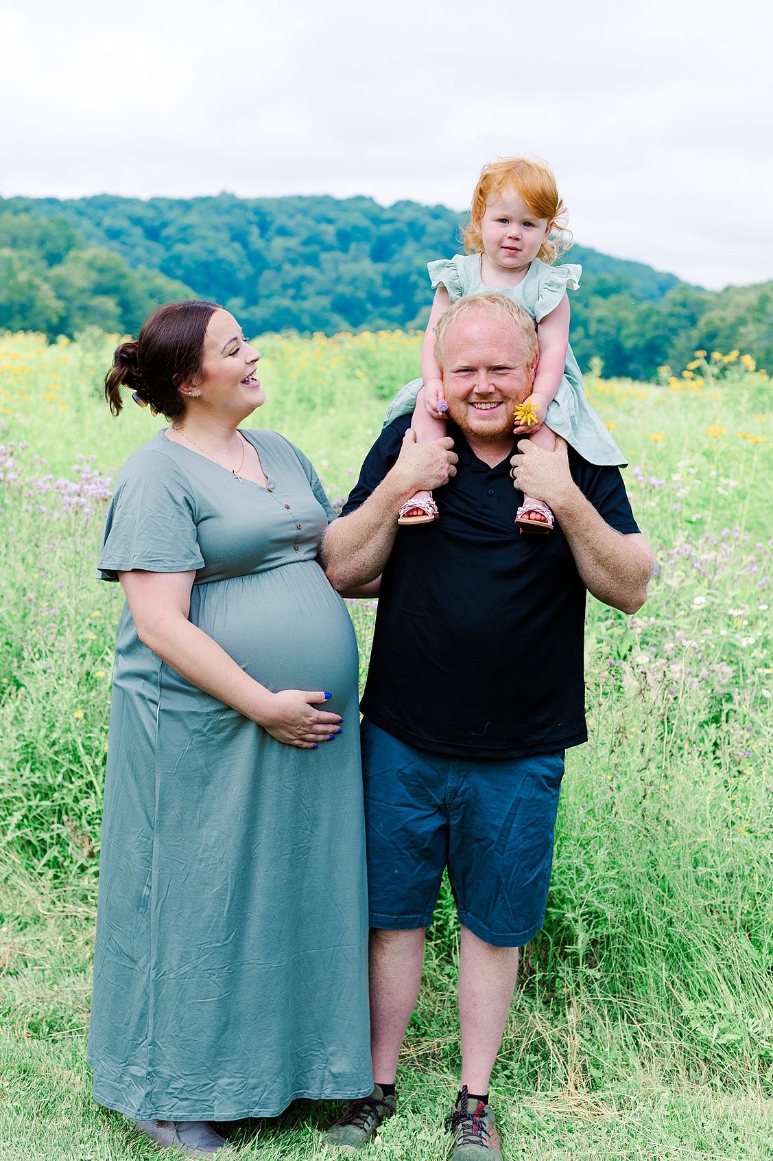 Mom holding her baby bump, dad holding big sister on his shoulders during an outdoor maternity photoshoot in Pittsburgh.