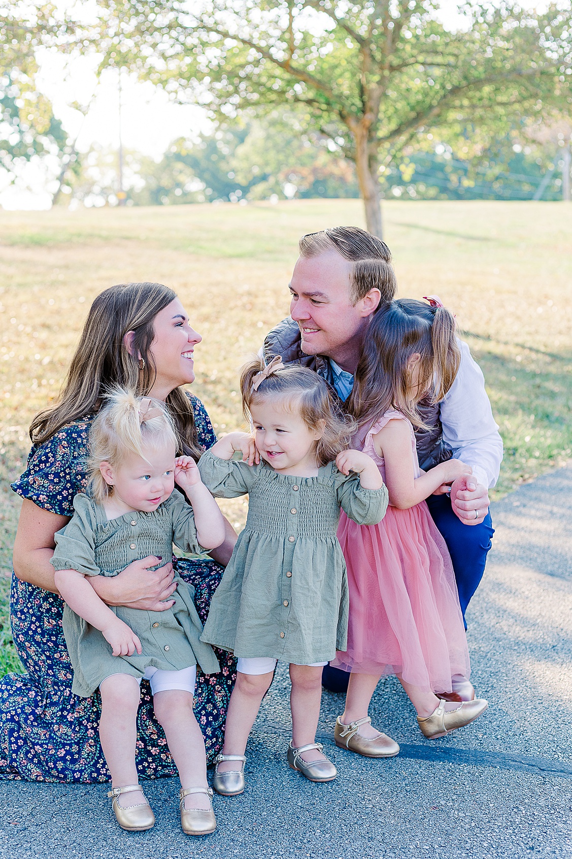 mom and dad are lovingly looking at each other while the girls do their own thing during a family photo session in Cranberry Township.