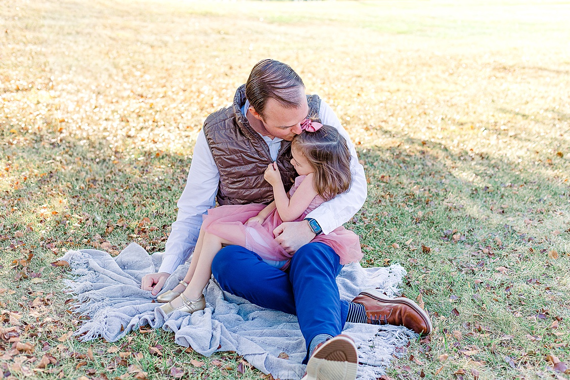 Dad kissing his oldest daughter while holding her on his lap.