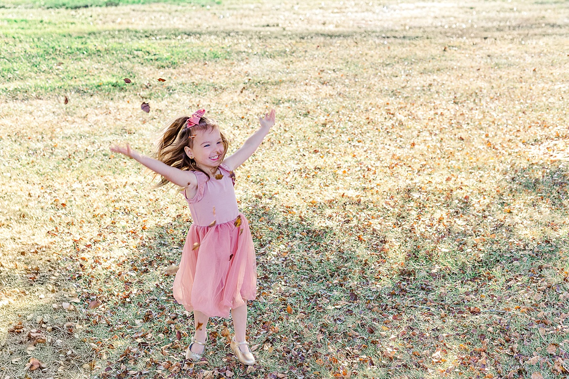 older sister is jumping up and down in the leaves during her family session in cranberry session.