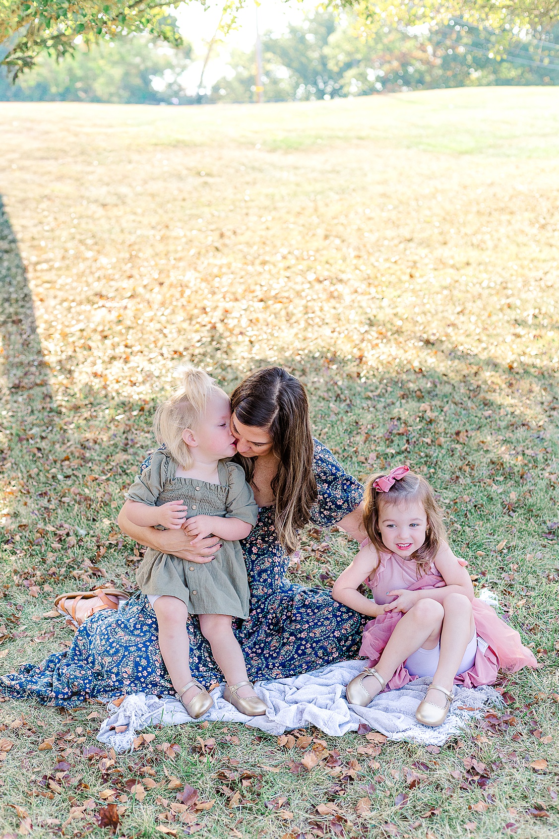 Mom is sitting on a blanket with her 2 out of 3 girls and the youngest is kissing her cheek. Sometimes the in between moments during Wexford Family Photography sessions are the best to capture.