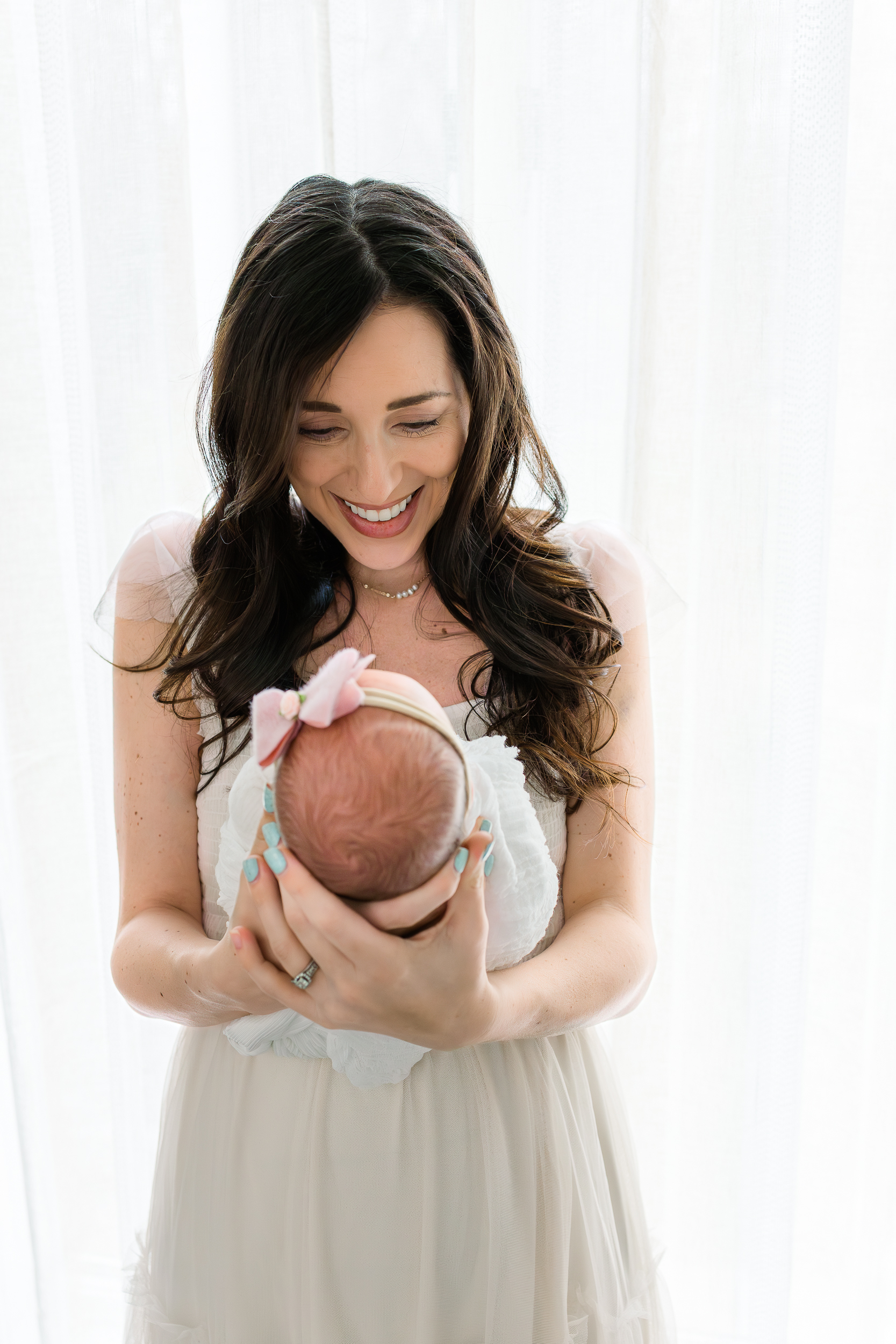 Mom holding her baby girl during her in home lifestyle newborn session in Pittsburgh.