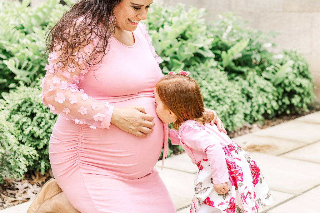 Toddler girl giving mom's baby bump a sweet kiss during a Wexford maternity photoshoot
