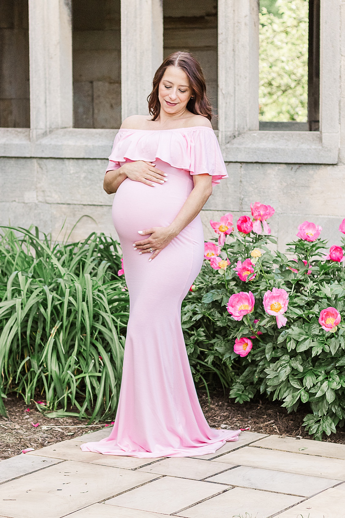 Figuring out what to wear to your maternity photoshoot doesn't need to be complicated, this beautiful mama to be is wearing a pretty pink dress.