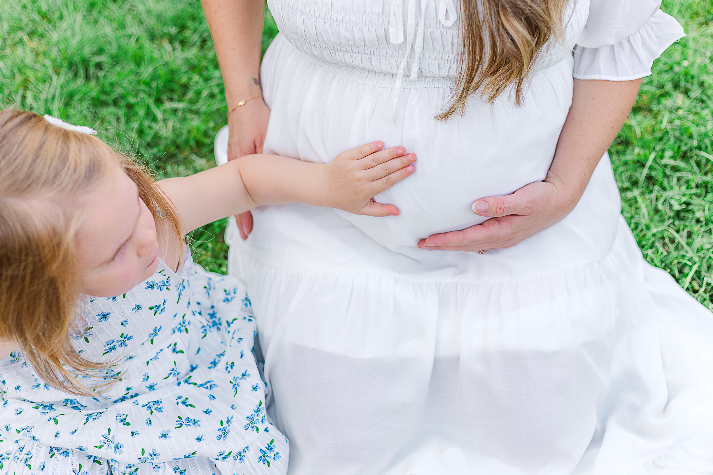 Little girl is feeling for her little brother to kick moms belly.  This was taken in Pittsburgh during a Maternity photography session. 